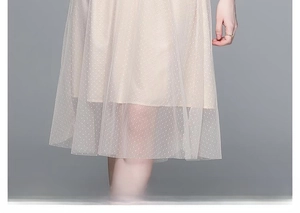 Close-up of beige tulle dress featuring polka dots and layered mesh hemline detail