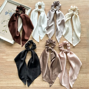 Set of 7 colorful satin scrunchies with long ribbons on a minimalist wooden background