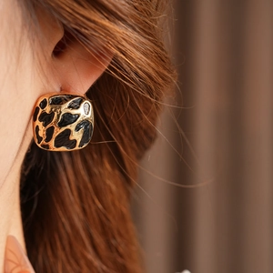 Gros plan de boucles d'oreilles carrées léopard avec base en métal doré sur modèle
