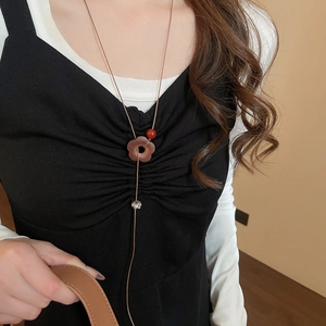 Détail d'un collier ethnique vintage avec pendentif fleur en bois et perle de cristal