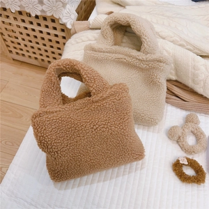 Détail de sacs à main en peluche type laine d'agneau marron et beige avec chouchous assortis