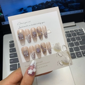 Detail of handmade nude pink nails with 3D white roses and pearls on a display card
