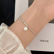Double-layered silver bracelet with a white pearl and moonstone on a woman's wrist