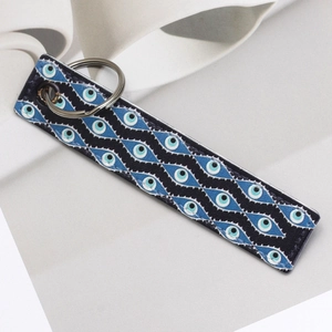 Macro view of blue Evil Eye pattern printed on a rectangular faux leather keychain