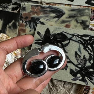 Close-up of vintage irregular silver ring pendant with black onyx stones in hand