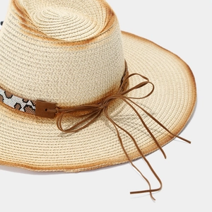 Detail of hand-woven straw hat with leopard pattern beadwork and a leather bow tie
