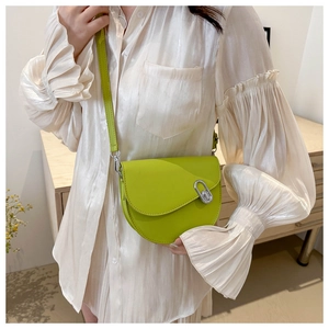 Model wearing a neon green saddle crossbody bag with silver hardware and matte finish