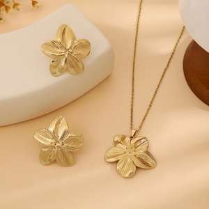 Close-up of golden flower jewelry set with detailed leaf texture on matte background