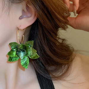 Detailed view of large green resin flower earrings with vintage gold metal ring link