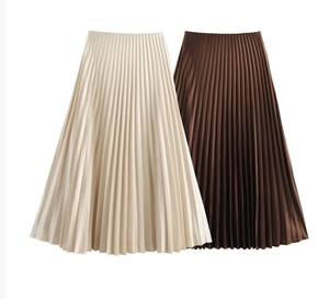 Detailed view of pleated texture on high-waisted midi skirts in beige and dark brown