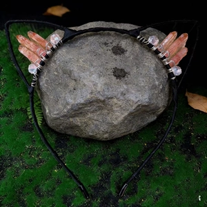 Detailed close-up of cat ear headband with orange crystals on a natural stone background