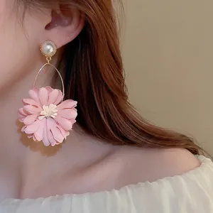 Elegant pink floral petal earrings with white pearls and gold accents on a female model