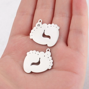 Detailed view of two baby footprint pendants with crystal inlay on a person's hand