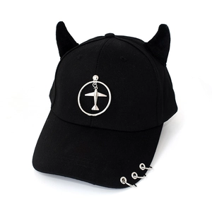 Detail of black baseball cap featuring devil horns and silver rings with plane pendant
