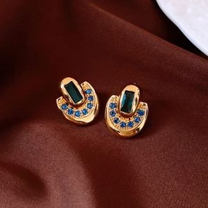 Détail des boucles d'oreilles fer à cheval plaquées or 18 carats avec gemme verte et cristaux
