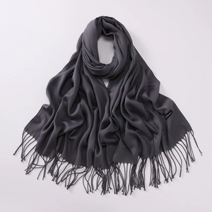 Close-up of dark grey pashmina scarf featuring fringe details and cashmere woven label