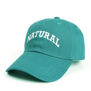 Detailed close-up of teal cotton baseball cap with white NATURAL embroidery and stitching