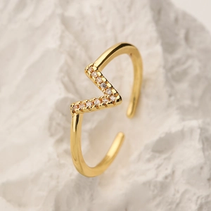 Adjustable gold plated geometric ring with cubic zirconia stones on stone background