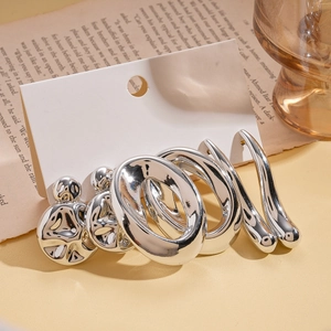 Macro shot of silver metal earring set featuring round studs and irregular hoops