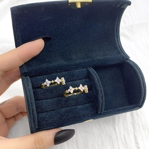 Detailed close-up of gold flower earrings with white gems in a blue velvet jewelry box