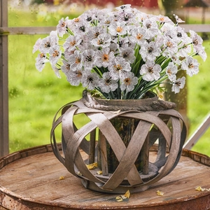Artificial white wildflowers in a rustic woven wooden basket on a vintage metal barrel