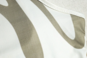 Close-up of ribbed knit texture with olive green printed graphic on white sleeveless dress