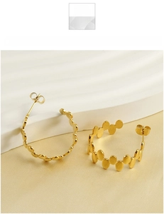 Detail of 18k gold plated titanium steel hoop earrings with relief circular texture