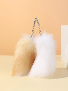 Close-up of fluffy oversized faux fox tail keychains in white and light brown fur