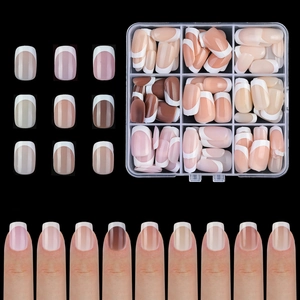 Macro shot of French tip press-on nail set in nude pink, brown tones with storage case