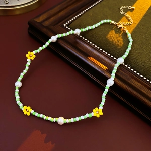 Macro view of beaded necklace with white pearls and yellow flower charms on metal chain