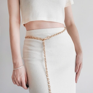 Detail of adjustable gold metal chain waist belt with lobster clasp on a white dress