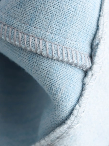Macro detail of the fine stitching and soft knit fabric texture on a light blue jacket