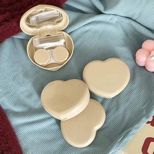 Detail view of heart-shaped contact lens case with mirror, tweezers and scoop inside