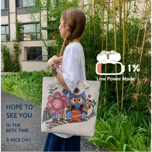 Outdoor shot of a large canvas tote bag with colorful owl embroidery and rope handles