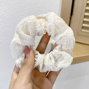 Close-up of white ruffled polka dot hair scrunchie showing fabric texture and pleats