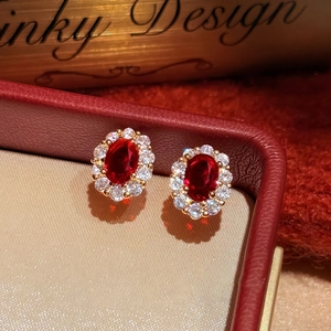 Macro shot of 18K gold plated oval red ruby earrings with sparkling zircon halo detail