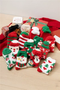 Detailed view of assorted Christmas coral fleece socks with festive patterns on wood