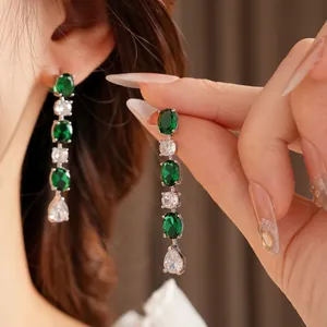 Boucles d'oreilles pendantes élégantes avec zircons vert émeraude et blancs en métal