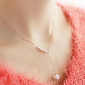 Elegant gold necklace with curved pearl bar and single large drop pearl on a model