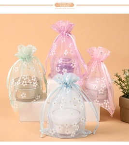 Drawstring organza gift bags with white floral prints in four pastel colors on a pedestal