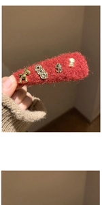 Detail of red plush hair clip with golden charms featuring a pony and rhinestone accents