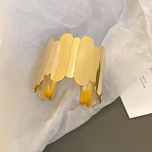 Detail of a minimalist irregular gold cuff bracelet with a polished mirror finish surface