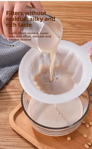 Close-up of fine mesh soy milk strainer filtering liquid over a wooden table