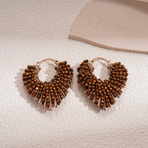 Macro shot of retro brown beaded heart earrings with intricate handmade weaving texture