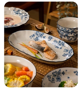 Detailed view of blue and white floral ceramic plates and bowls with cooked fish