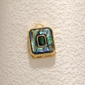 Detail of rectangular gold pendant with green gemstone and iridescent abalone shell inlay