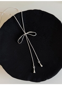 Dettaglio della collana d'argento con pendente a fiocco e nappe su vassoio nero