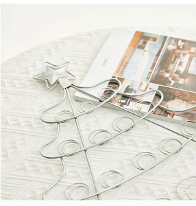 Close-up of a 50cm silver metal wire Christmas tree photo holder on a white tablecloth