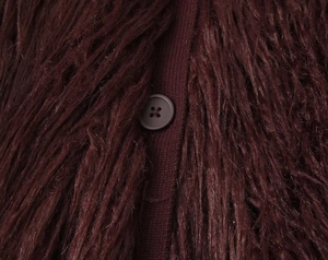 Macro shot of faux fur texture and burgundy button closure on high-quality knit cardigan