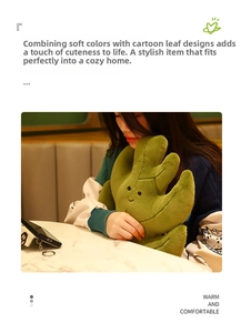 Detail of green leaf plush pillow featuring a stitched smile and soft fabric texture